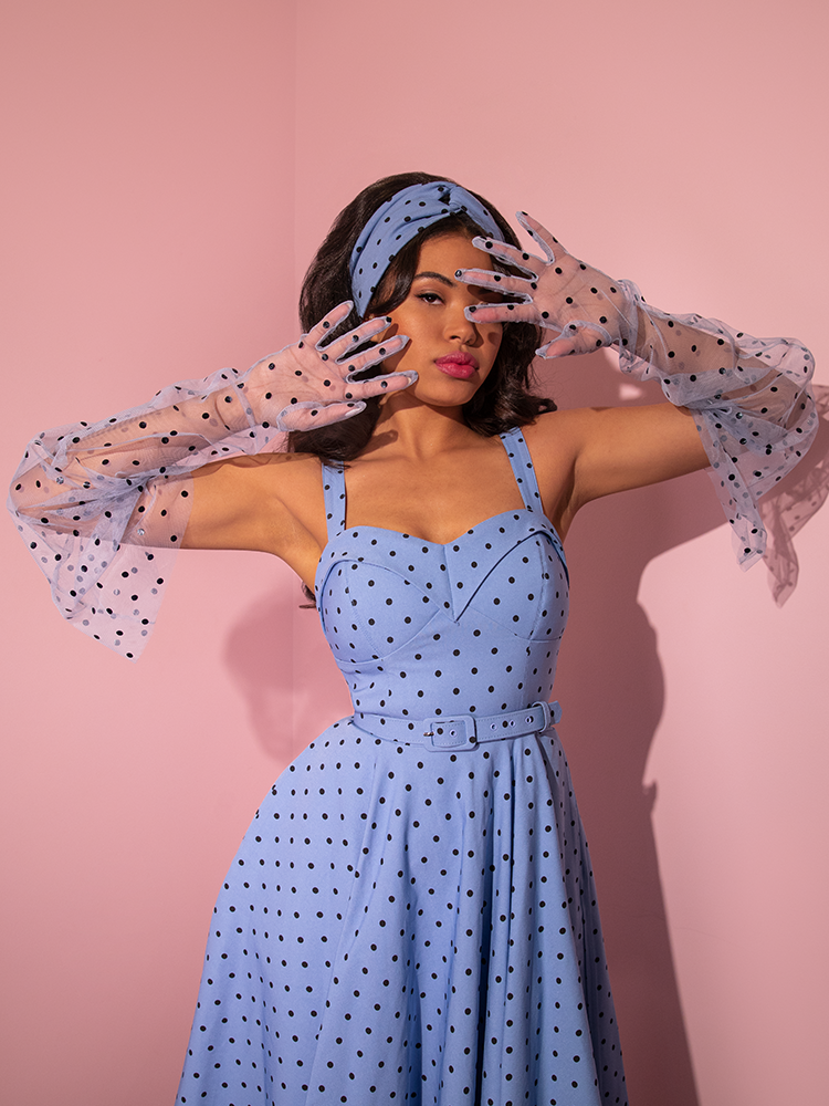 A model slightly obscuring her face with the Mesh Polka Dot Full Length Gloves in Sunset Blue.