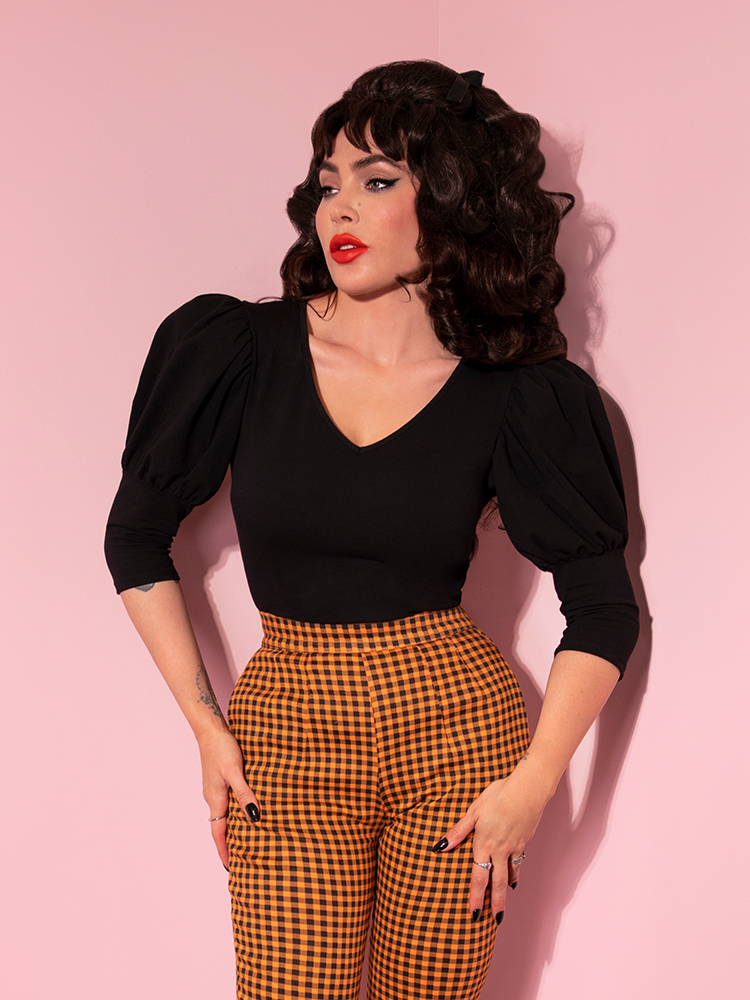 Micheline Pitt staring off into the distance, pulls together a classic mod look with a retro style top and gingham print pants.