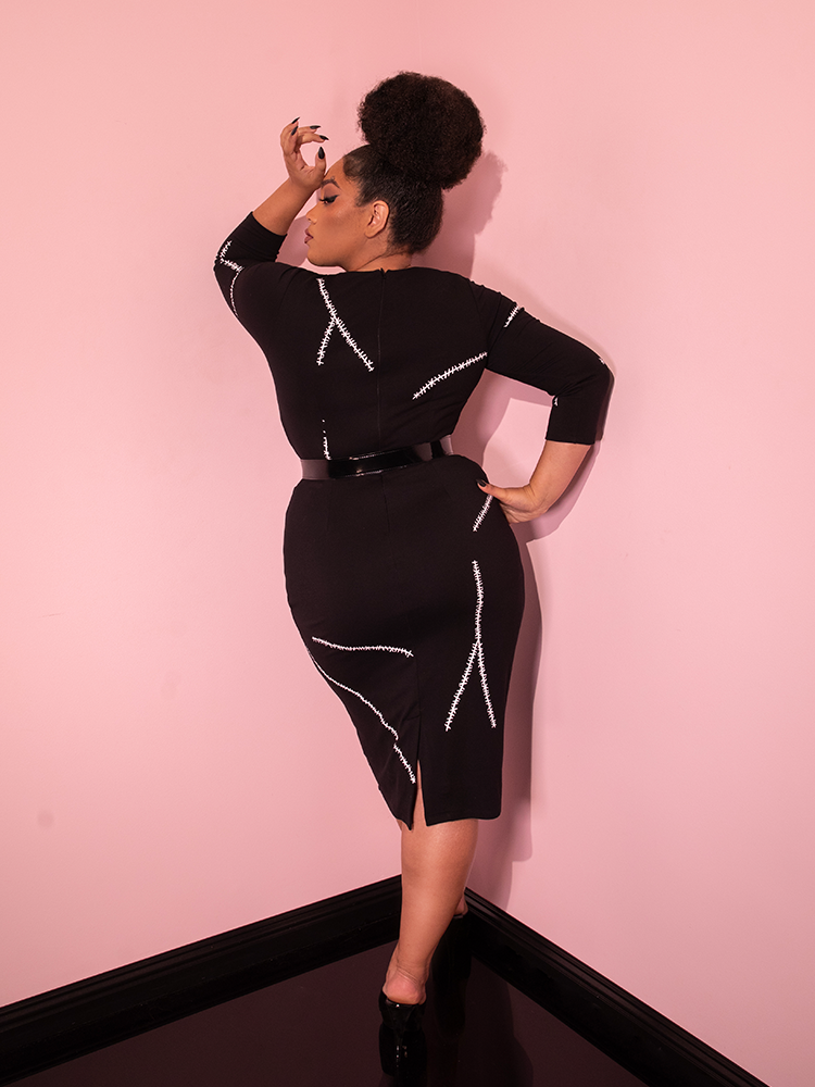 Model turned away from the camera to show off the back of the ATMAN RETURNS™ Catwoman Stitch Wiggle Dress from retro dress brand Vixen Clothing.