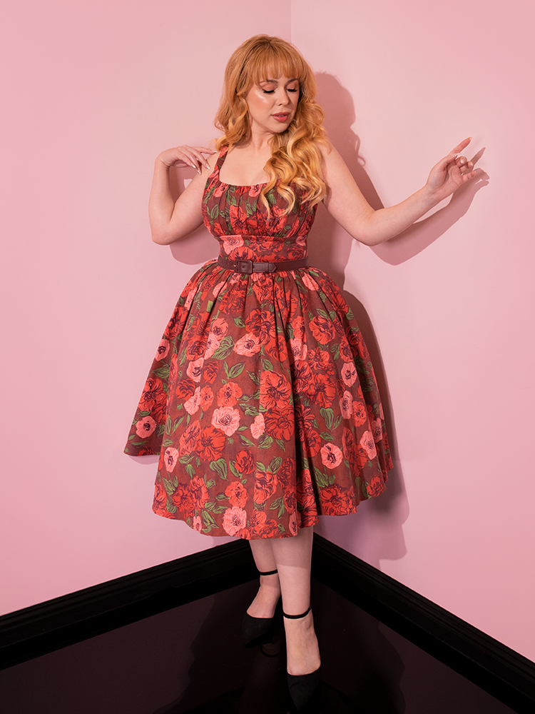 In a delightful display of retro elegance, beautiful models playfully pose in the Chocolate Rose Print Ingenue Dress by the renowned retro dress brand Vixen Clothing.