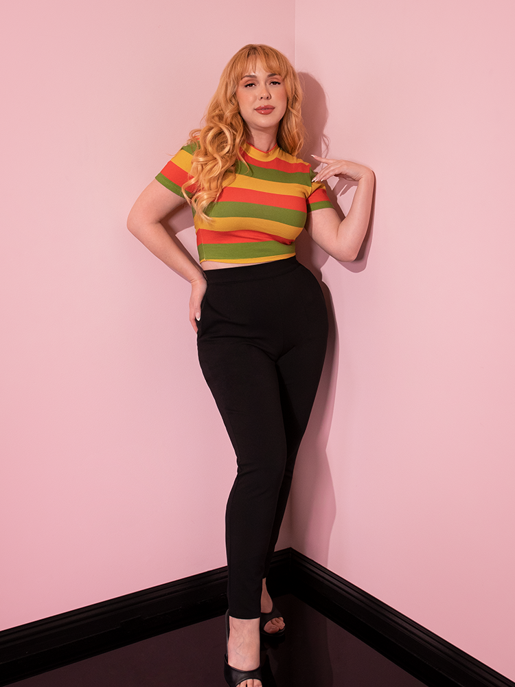 Full length shot of the model wearing a retro style outfit including the Bad Girl Crop Top in Orange/Yellow/Avocado Stripes.