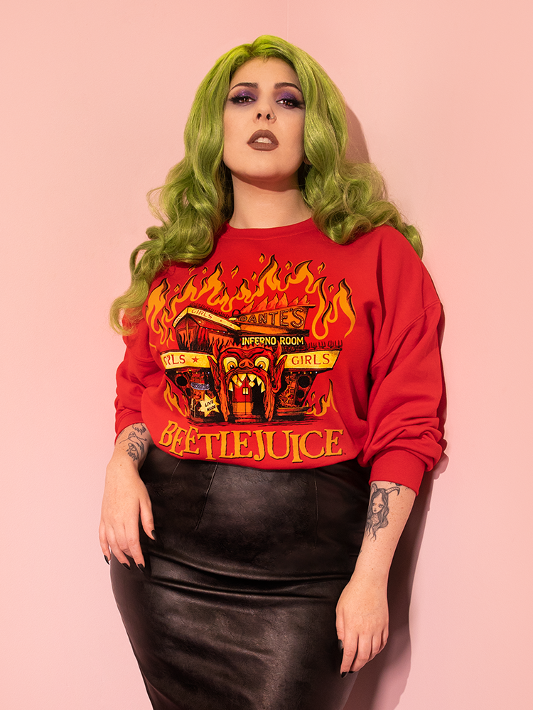 Green haired model posing in the BEETLEJUICE™ - Dante's Inferno Sweatshirt (Unisex) paired with a vegan leather skirt - all items from retro style clothing brand Vixen Clothing.