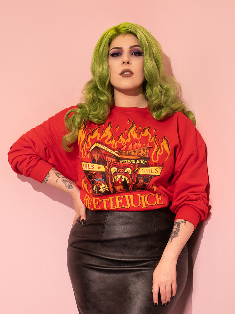 Green haired model posing with one hand on her hip and the other resting on her thigh while wearing the Dante's Inferno Sweatshirt over a vegan leather black skirt.