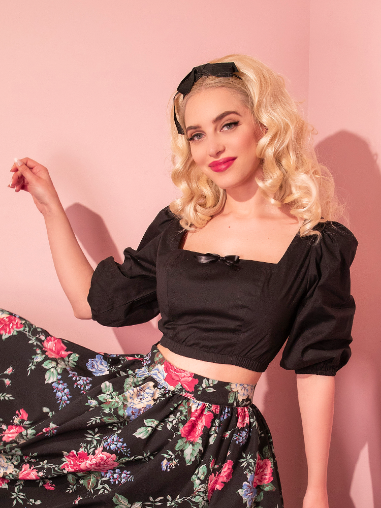Sofia smiles as she swings the her skirt around that goes perfectly with the all-new Darling Crop Top in Black from retro clothing company Vixen Clothing.