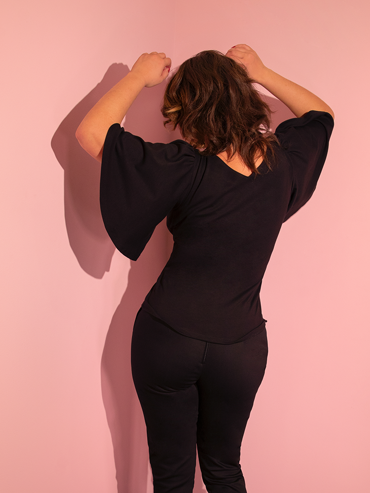 The back of the Deadly Kiss Top in Black being worn by Francesca who has her arms raised to show off the open and comfortable sleeves.
