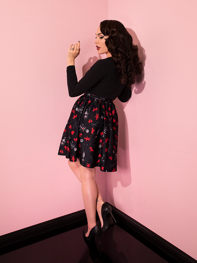 Micheline Pitt turned away from the camera to show off the back of the EDWARD SCISSORHANDS Skater Skirt in “I am not complete” Novelty Print.