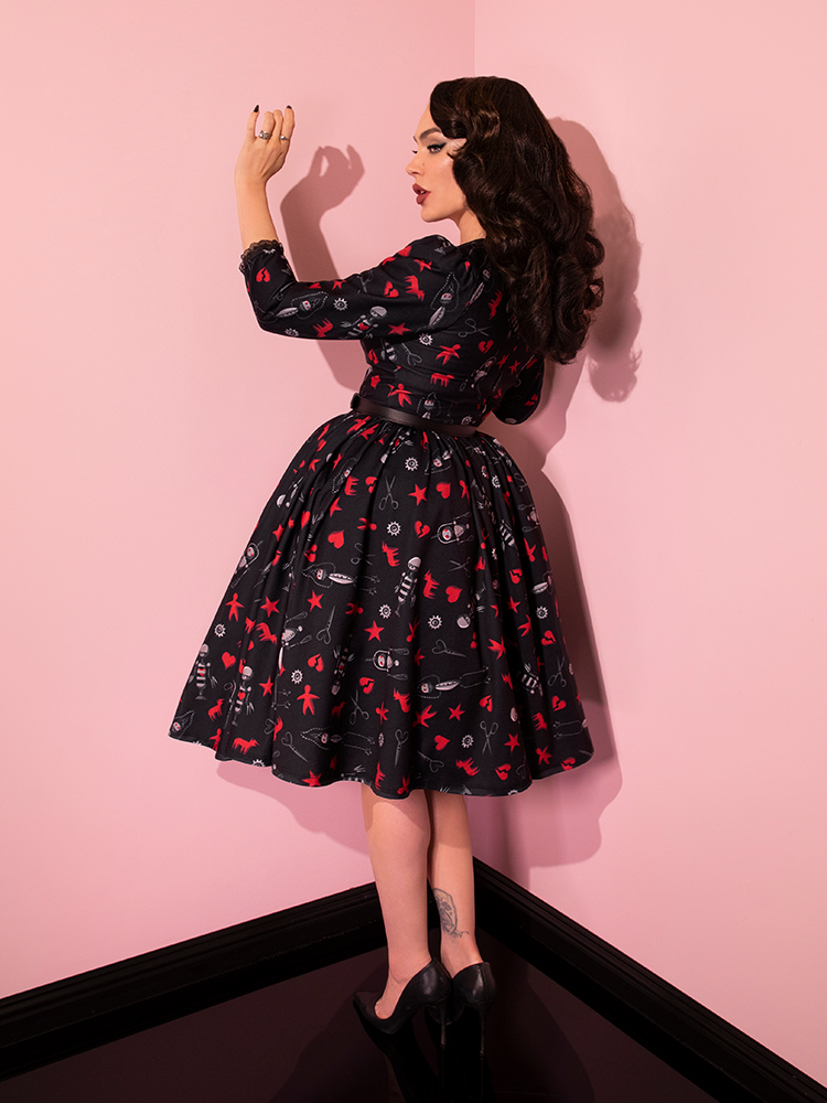Full length shot of Micheline Pitt turned away from the camera while wearing the EDWARD SCISSORHANDS Storytime Swing Dress in “I am not complete” Novelty Print.