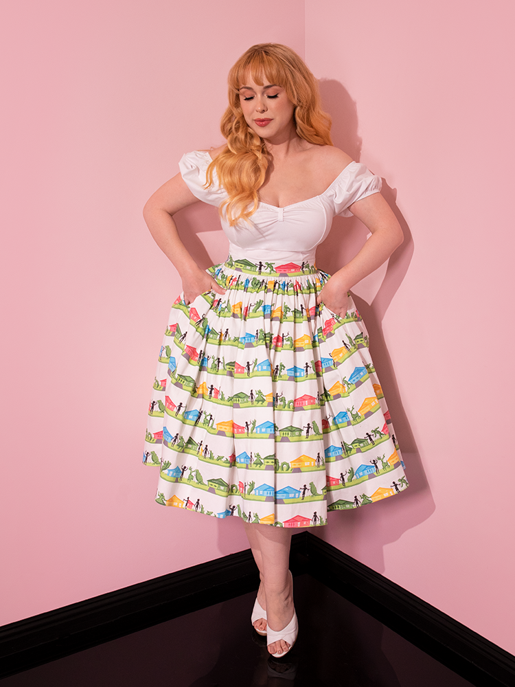 Full length shot of female model wearing the EDWARD SCISSORHANDS Swing Skirt in Suburban Topiary Novelty Print with her hands tucked firmly into her pockets. 