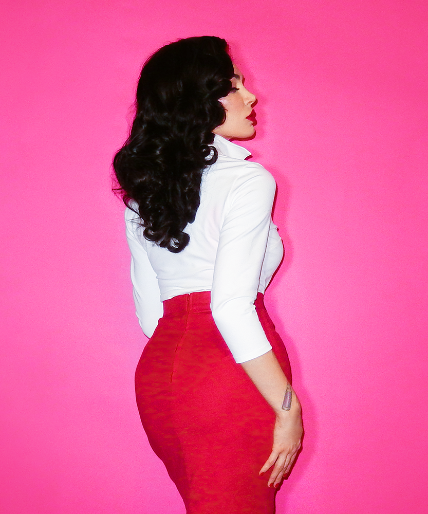 Profile shot of Micheline Pitt in the Vixen Top in White and red pencil skirt.