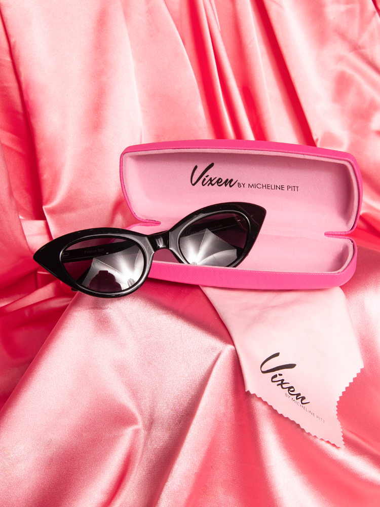 Stylized shot of the Fashion Doll Cat Eye Sunglasses in black placed on a pink satin background.