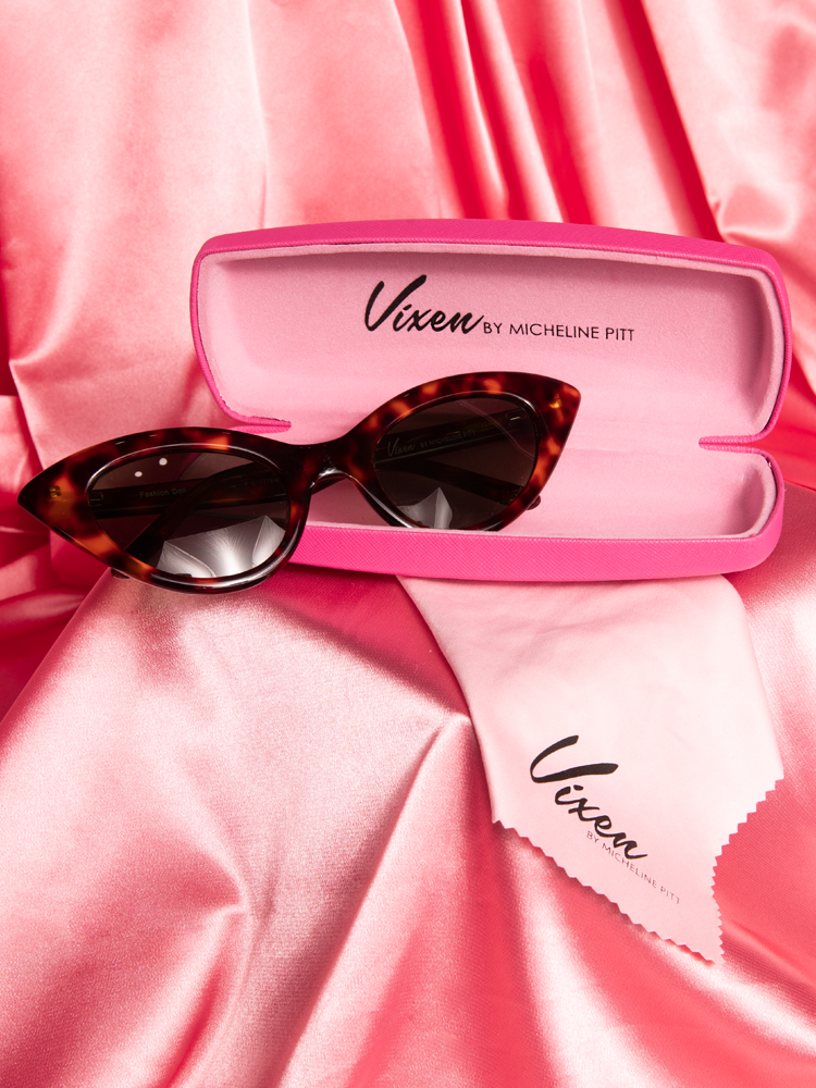 Stylized shot of the Fashion Doll Cat Eye Sunglasses in tortoise shell placed on a pink satin background.