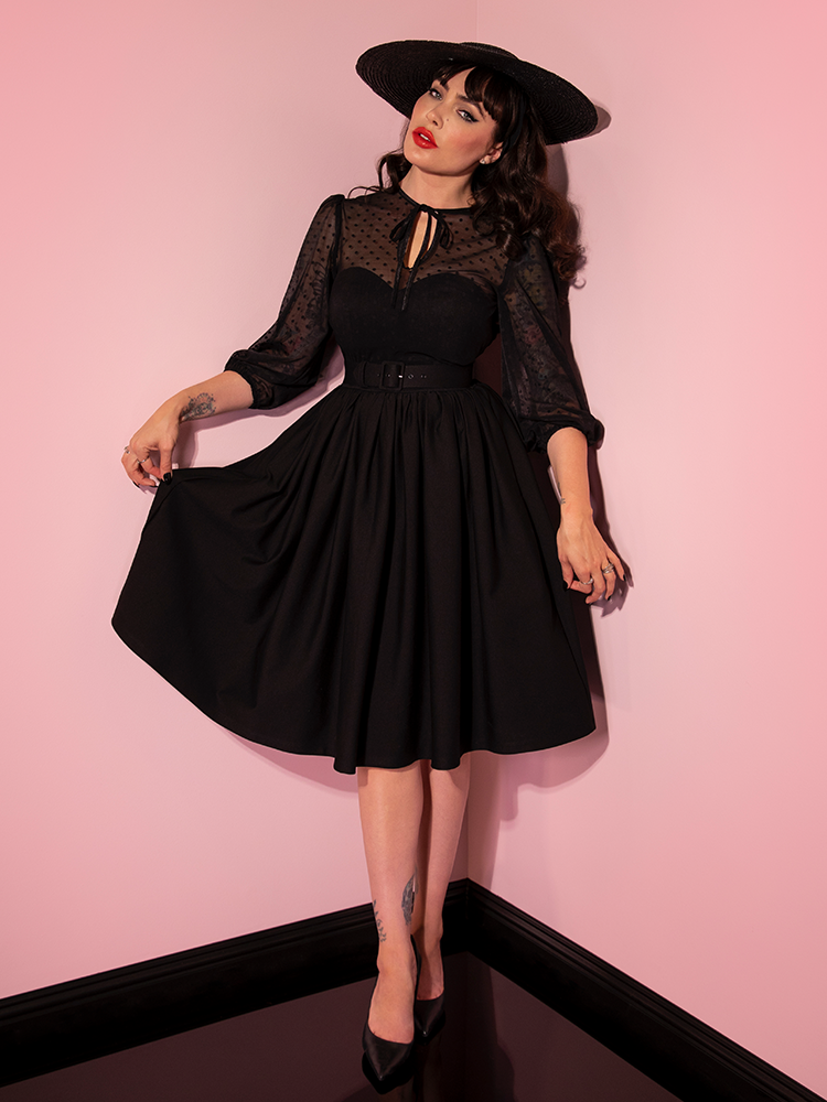 Micheline Pitt showing off the skirt on the Frenchie Swing Dress in Black from Vixen Clothing.