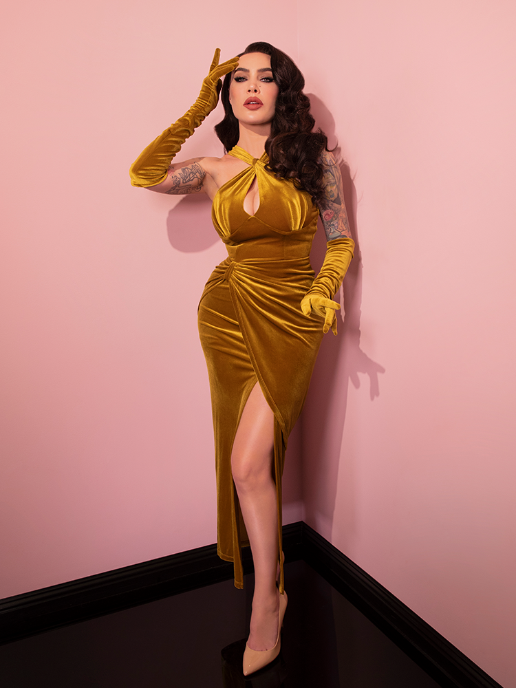 Micheline is in a pink room with her hand on her brow while wearing the Golden Era gown and glove set.