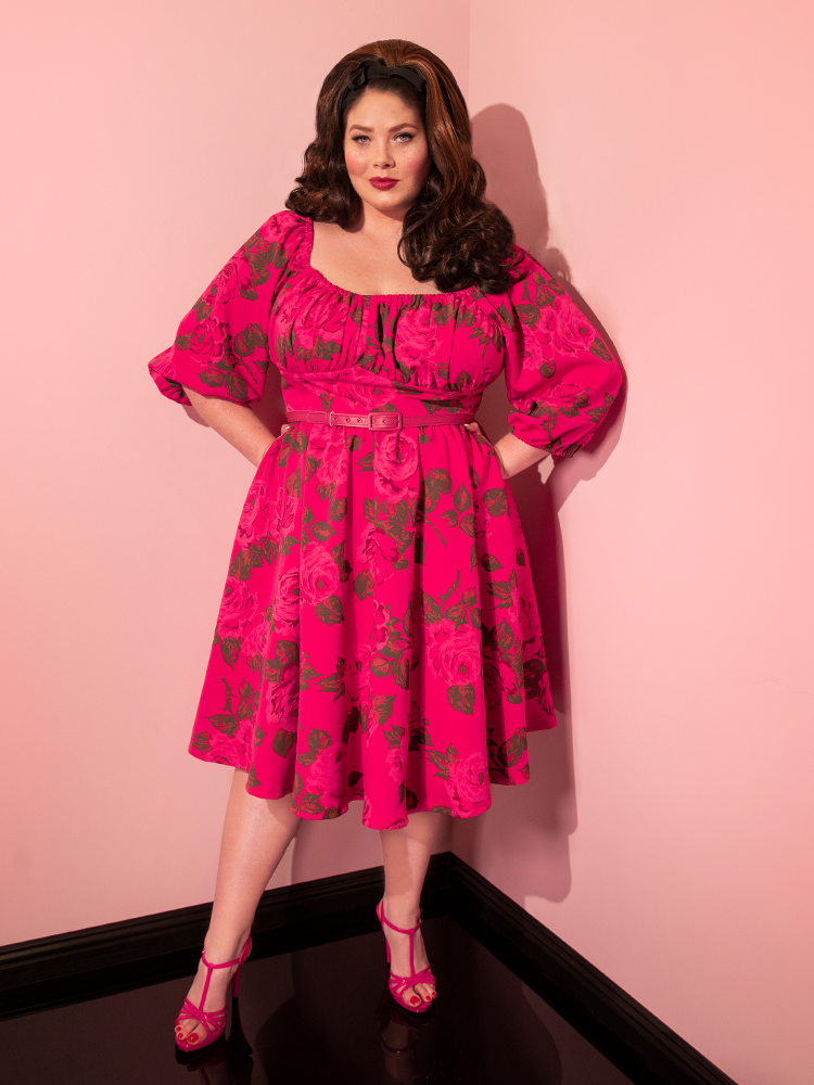 Full length shot of brunette model wearing a hot pink retro style dress from Vixen Clothing.