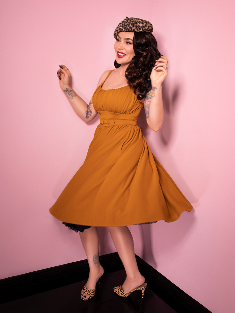 Micheline Pitt spins in the mustard print Ingenue Dress from vintage clothing retailer Vixen Clothing.