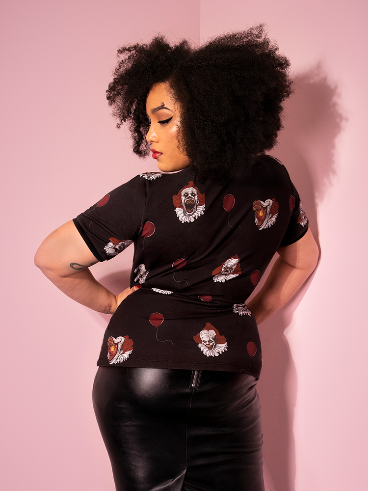 Turned away from the camera, Ashleeta shows off the back of the Pennywise ringer tee by Vixen Clothing.