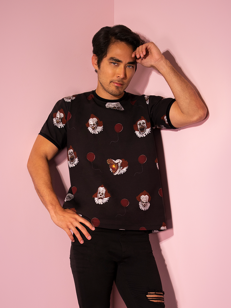 With his hand on his forehead, Ethan models the Pennywise ringer tee by Vixen Clothing.