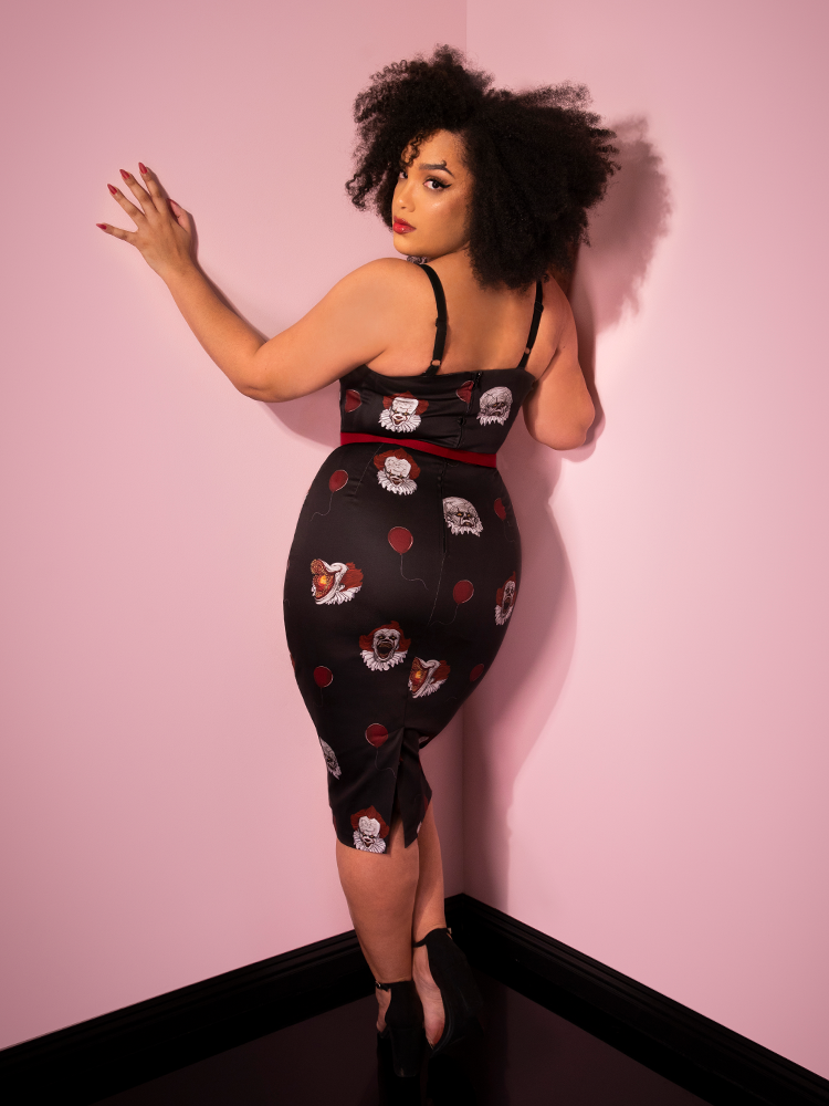 Turned away from the camera and looking over her shoulder, Ashleeta shows off the back of the Pennywise sweetheart wiggle dress by Vixen Clothing.