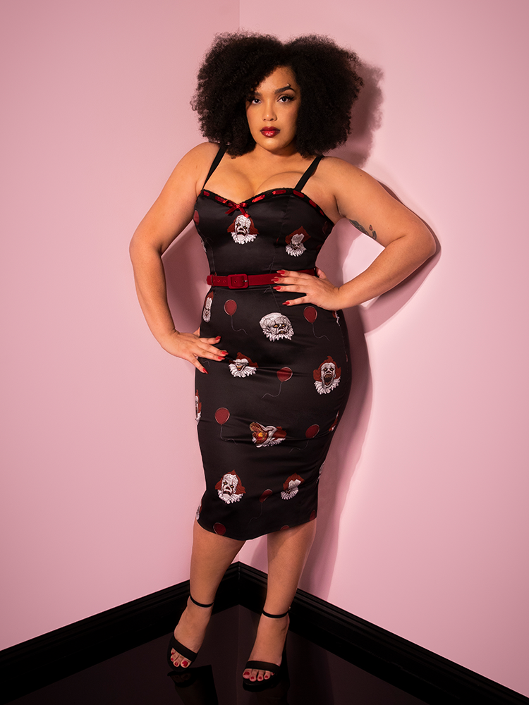 In a proud stance with her hands on her hips, Ashleeta models the Pennywise sweetheart wiggle dress by Vixen Clothing.
