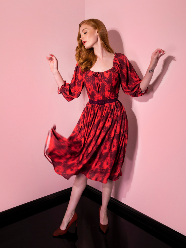 With her hands in the air, Emily models the Pennywise cottage dress by Vixen Clothing.