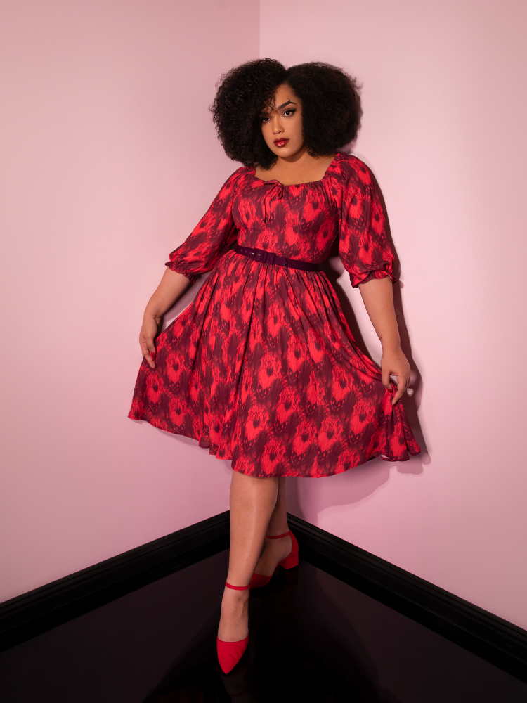 Fanning the skirt out with her hands, Ashleeta models the Pennywise cottage dress by Vixen Clothing.