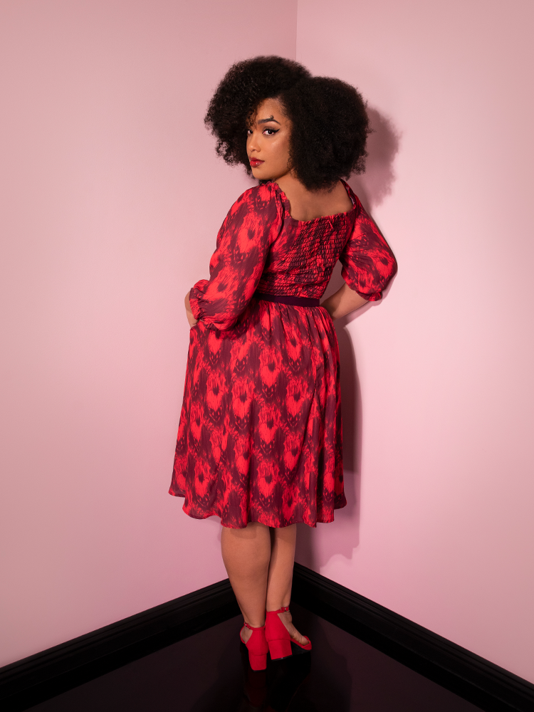Turned away from the camera and looking over her shoulder, Ashleeta models the Pennywise cottage dress by Vixen Clothing.