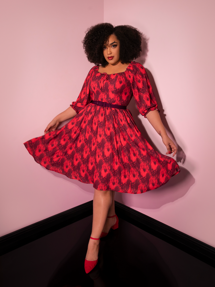 Holding out the skirt with her hands, Ashleeta models the Pennywise cottage dress by Vixen Clothing.