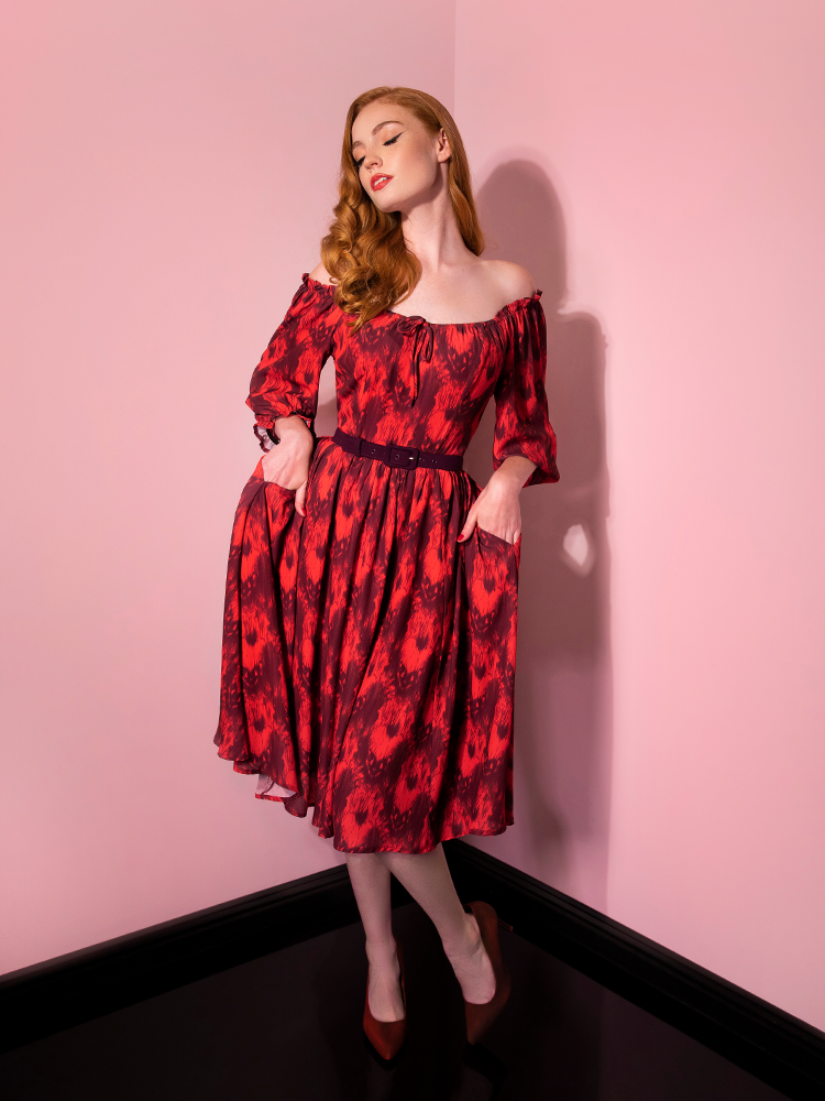 Looking down with both hands in her pockets, Emily models the Pennywise cottage dress by Vixen Clothing.