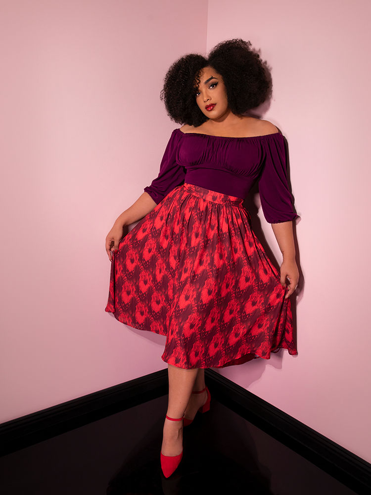Using her hands to fan out her skirt, Ashleeta models the Pennywise cottage skirt by Vixen Clothing.