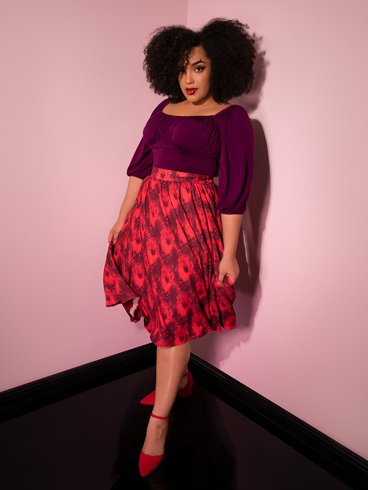 Looking at the camera with her hands on her skirt, Ashleeta models the Pennywise cottage skirt by Vixen Clothing.