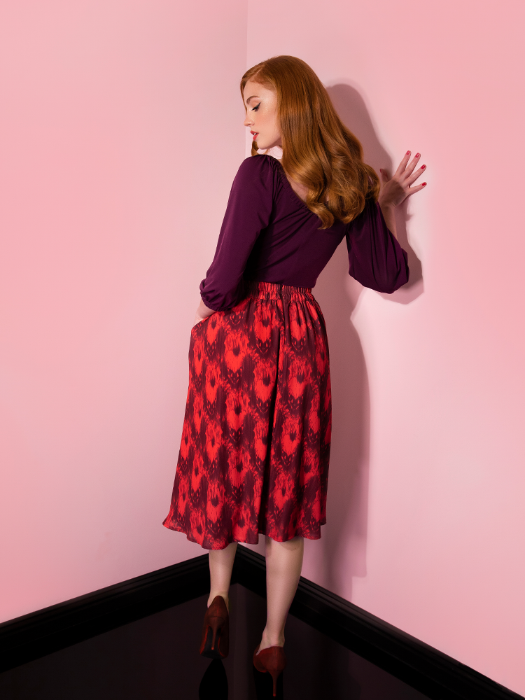 Turned away from the camera while looking down, Emily models the Pennywise cottage skirt by Vixen Clothing.