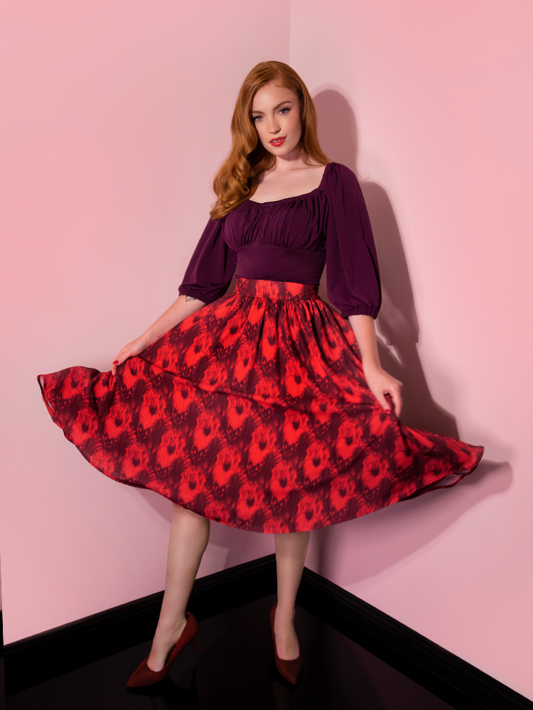 Twirling while holding her skirt with her hands, Emily models the Pennywise cottage skirt by Vixen Clothing.