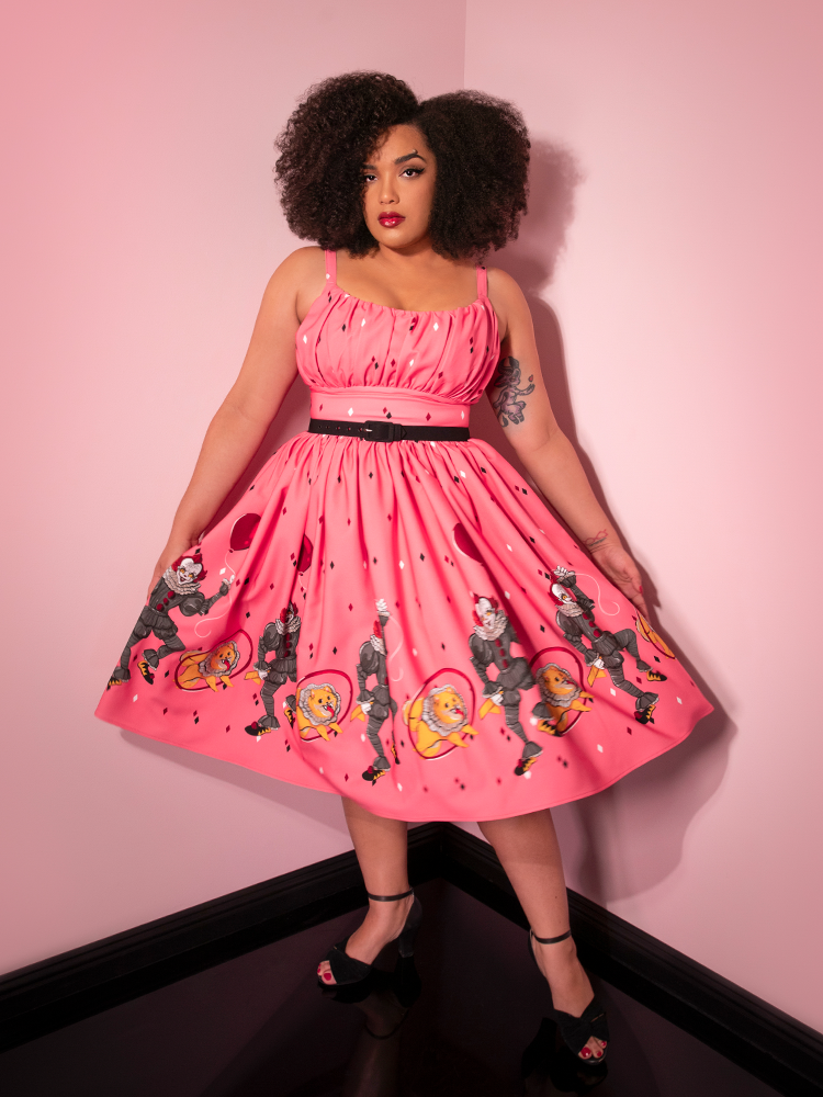 Stopping mid twirl, Ashleeta models the Dancing Clown Ingenue swing dress in pink by Vixen Clothing.