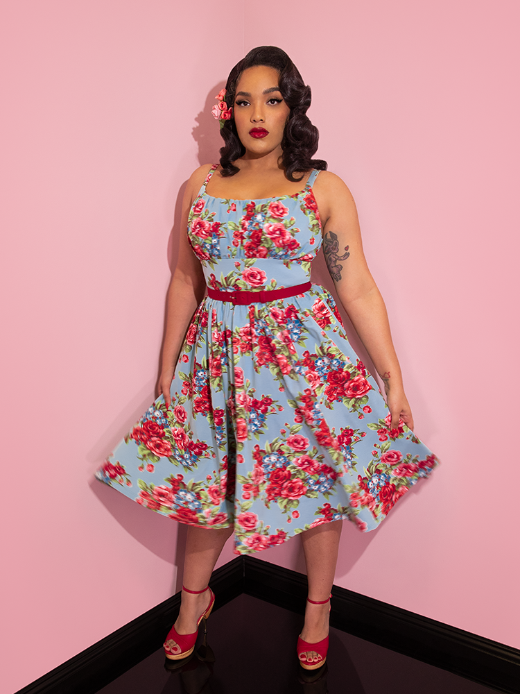 Ashleeta with flowers in her hair modeling the Vixen Clothing Ingenue dress in blue and red rose print.