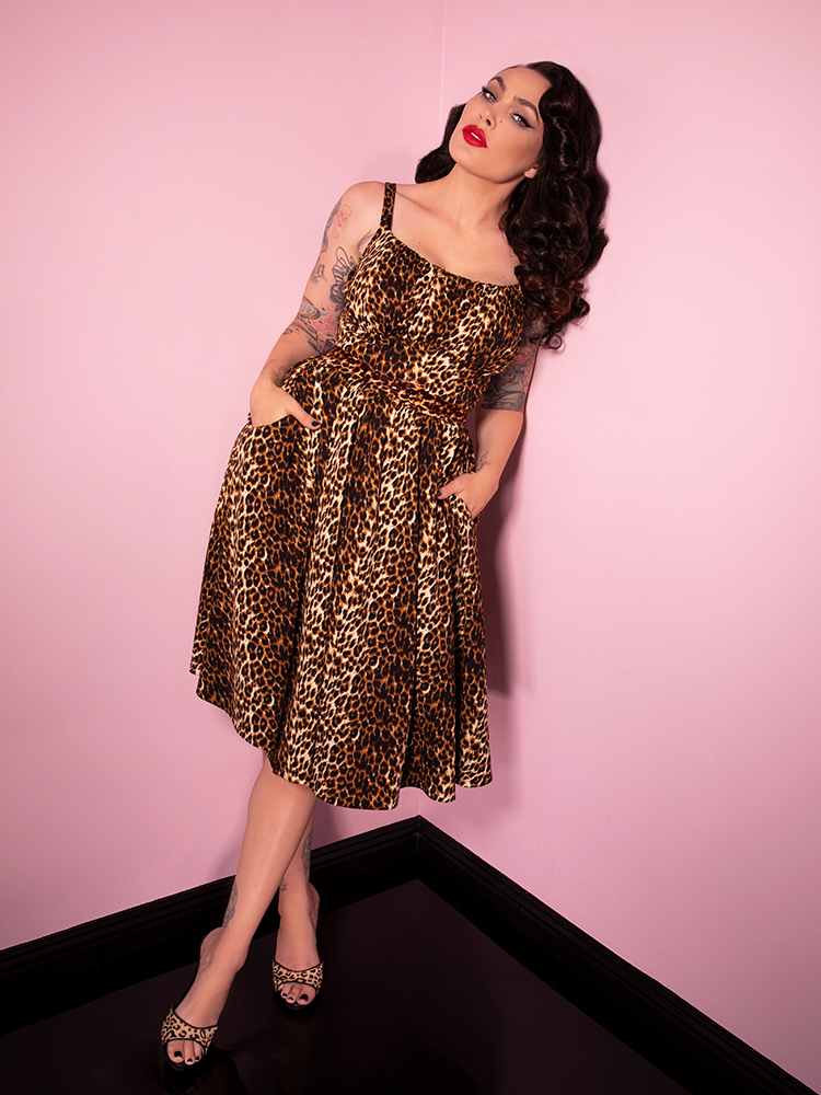 Posed with her hands in her pockets and leaning against a wall, Micheline Pitt looks gorgeous in the latest vintage inspired dress from Vixen Clothing.