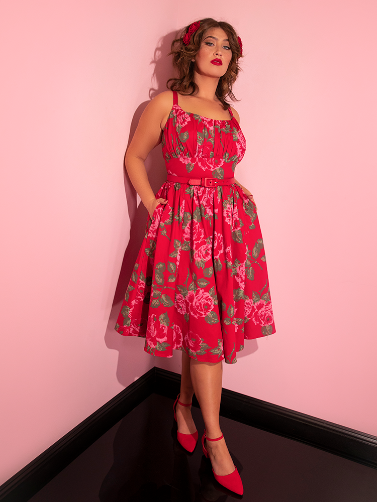 Francesca with her hands in the pockets of her Ingenue Swing Dress in Vintage Red Rose Print from Vixen Clothing.