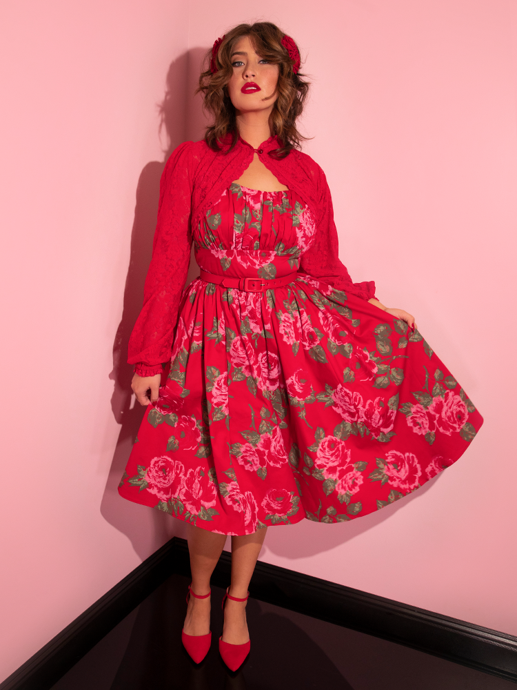 Full length shot of Francesca holding out the skirt of her Ingenue Swing Dress in Vintage Red Rose Print to show off to gorgeous print.