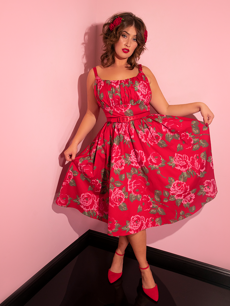 Francesca pulls out on either side of the Ingenue Swing Dress in Vintage Red Rose Print to show off the gorgeous red rose print.