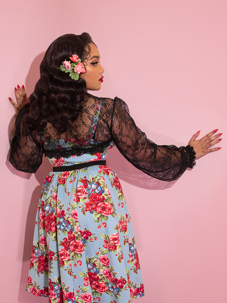 A shot of Ashleeta facing away from the camera while wearing the Vixen Vintage Lace Bolero in Black and retro floral dress.