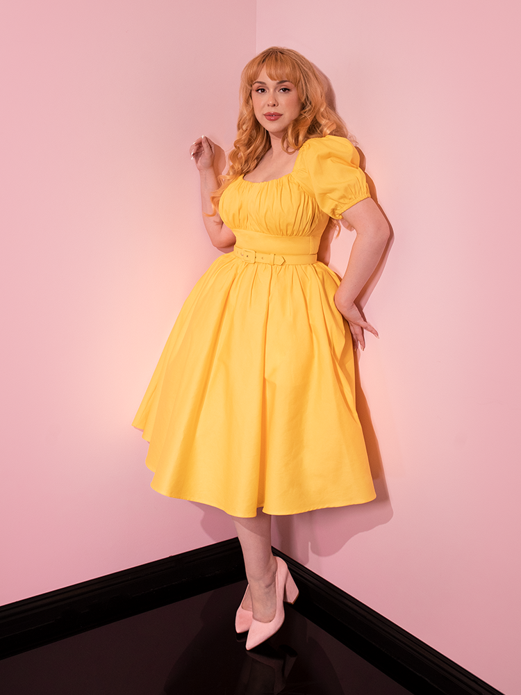 Full length shot of model posing in a retro style dress from Vixen Clothing - Lakeland Dress in Yellow.