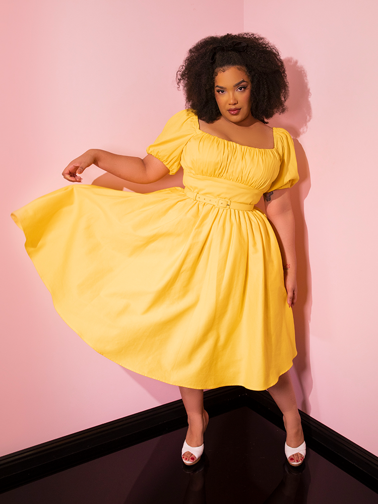 Model tosses out the skirt on the Lakeland Dress in Yellow providing a great glimpse of the vibrant color.
