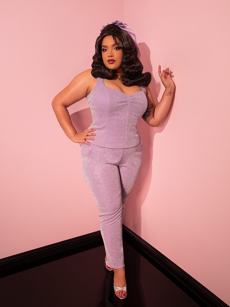 The Lilac Lurex Cigarette Pants from Vixen Clothing take center stage as the female model confidently shows them off, capturing attention with their retro allure.