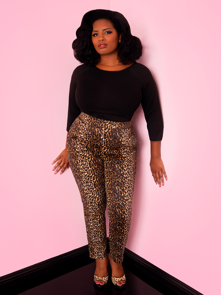 A full length shot of Aretina modeling the cigarette pants in leopard print by Vixen Clothing paired with a black top.