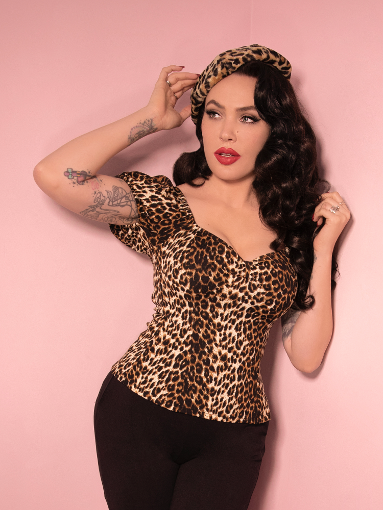 With her smoldering gaze and sultry stance, Micheline Pitt proves that the Powder Puff Top in Wild Leopard Print from Vixen Clothing is a must-have statement piece.