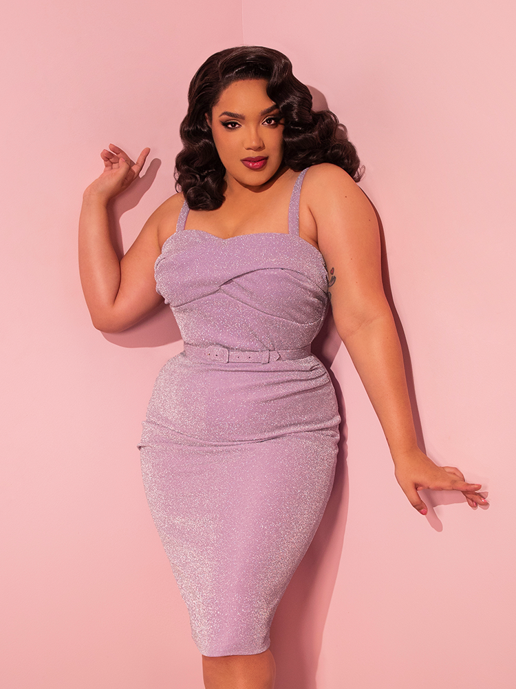 Embracing retro glamour, the buxom model confidently showcases the Jawbreaker Wiggle Dress in Lilac Lurex, an exquisite creation by Vixen Clothing, the renowned retro dress maker.