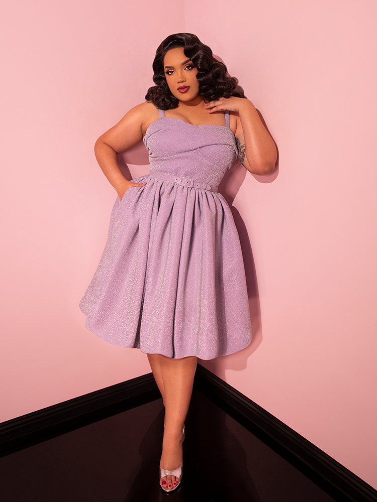 Mesmerizing onlookers, the lovely female showcases her style in the retro-chic Jawbreaker Swing Dress in Lilac Lurex, an irresistible offering from Vixen Clothing, the iconic brand known for its retro dress collection.