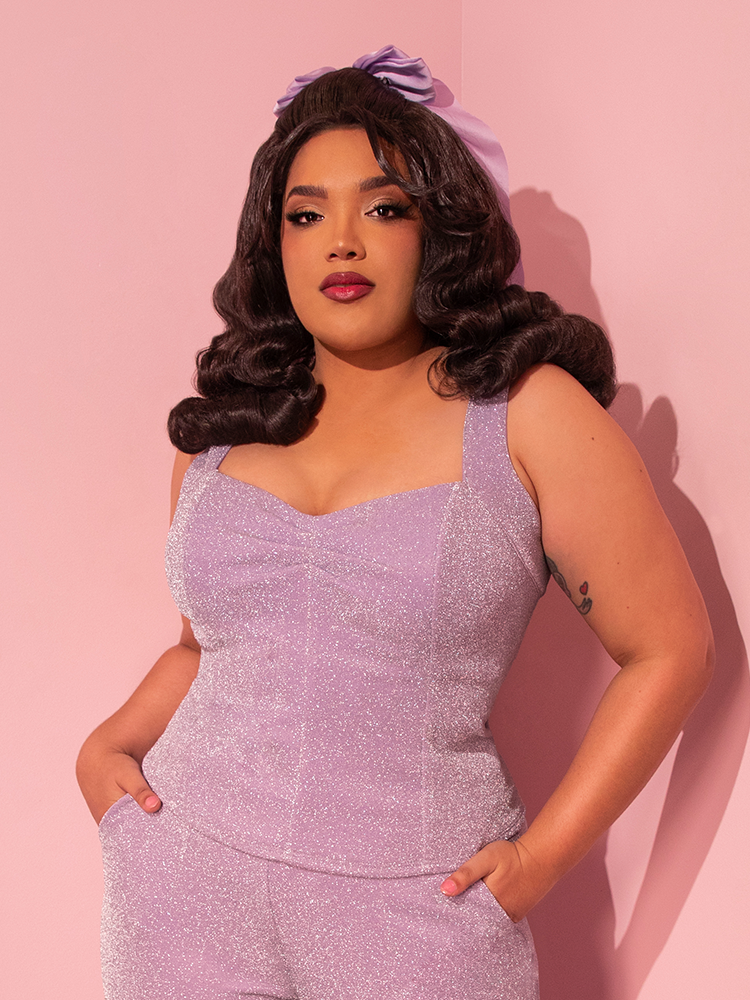 Catching the eye with seductive allure, the female model elegantly showcases Vixen Clothing's Vamp Top in Lilac Lurex, evoking a retro vibe.