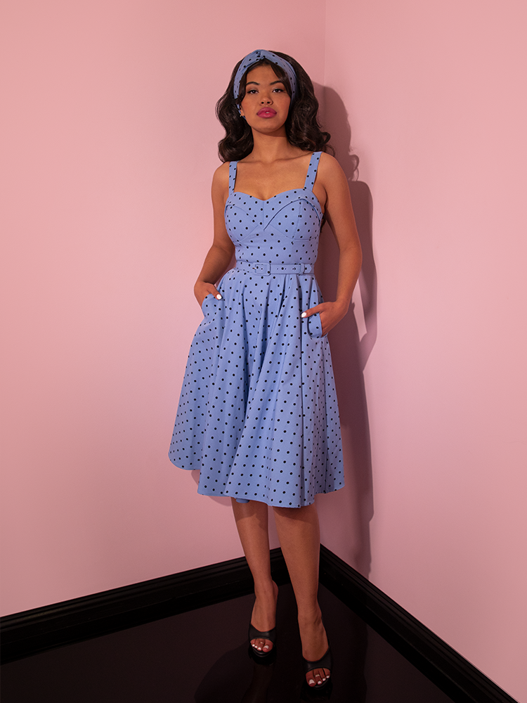 Full length shot of model wearing the Maneater Swing Dress in Sunset Blue Polka Dot with her hands placed into the pockets.