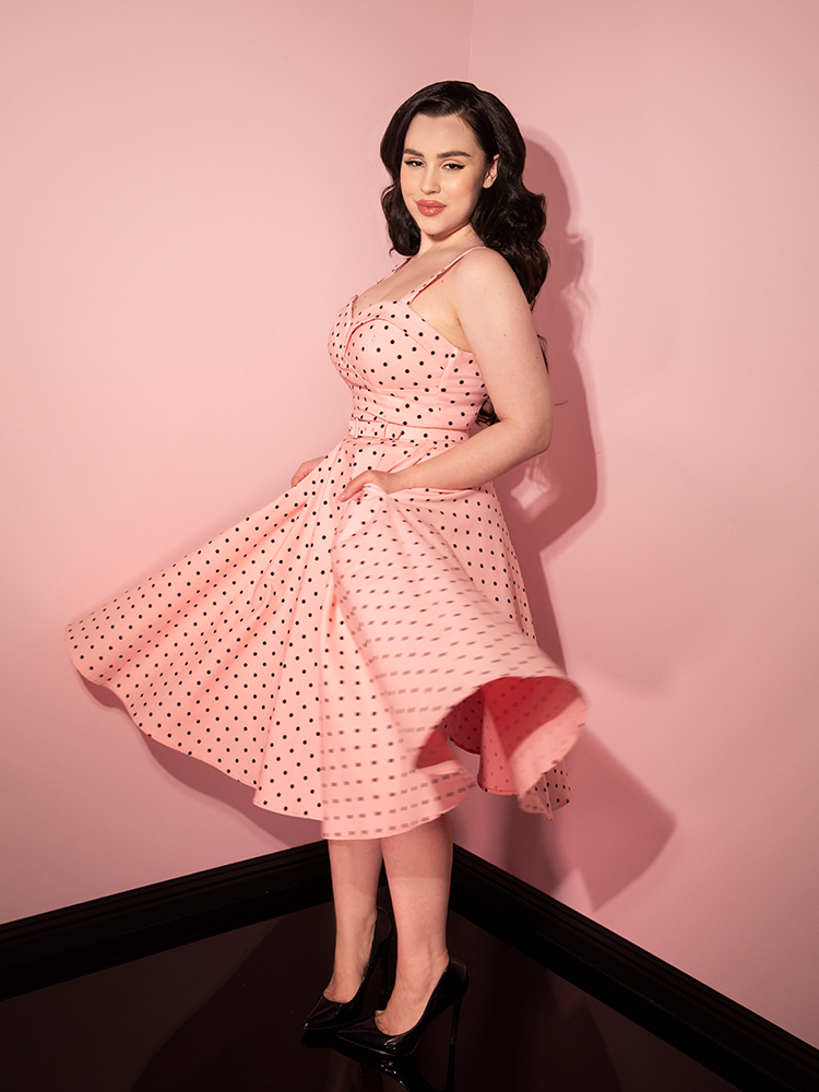 Rachel twirling in the Maneater Swing Dress in Rose Pink Polka Dot from retro clothing company Vixen Clothing.