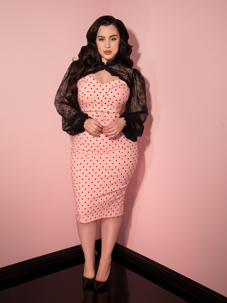 Rachel Sedory standing with a black lace bolero on top of her pink polka dot retro style dress.